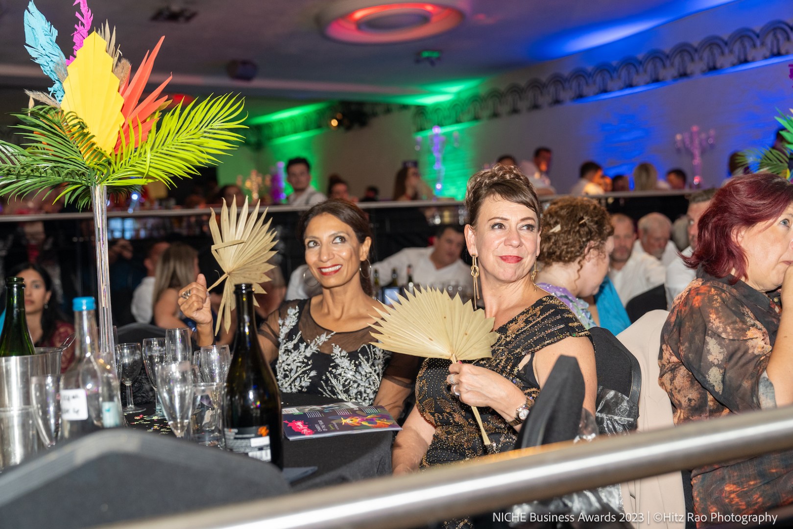 Female guests sit fanning themselves at a posh dinner table