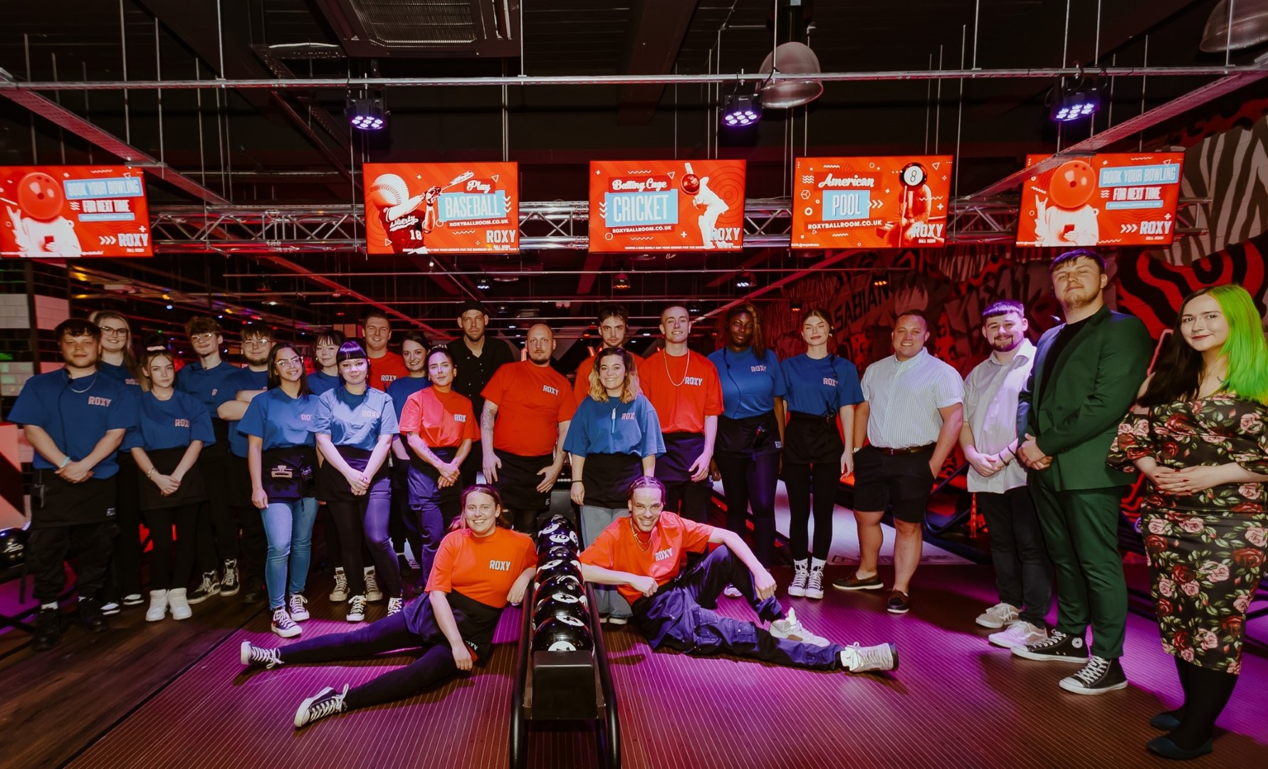 Staff gather in orange t-shirts to pose for a photo at the opening of the Roxy Ball Room in Leicester