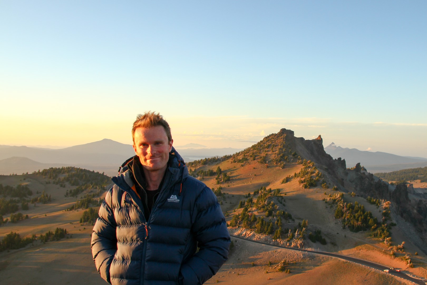 James Adler stands in front of a hilly landscape at dusk